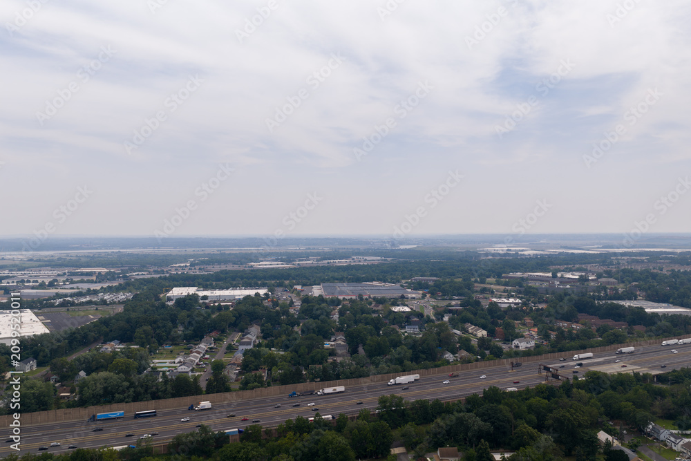 Fototapeta premium Aerial view of multi-lane highway traffic near suburban residential and industrial areas