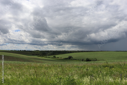 Dramatic storm clouds above rolling green countryside