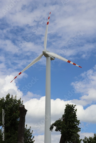Modern wind turbine against blue sky with white clouds