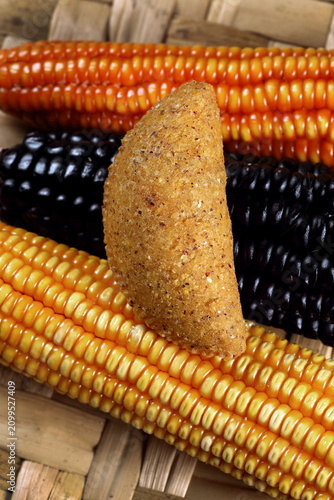 Foto Cornmeal mush pastry served on ears of corn of various colors.