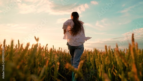Fotografie Kid girl playing runs wheat field in countryside