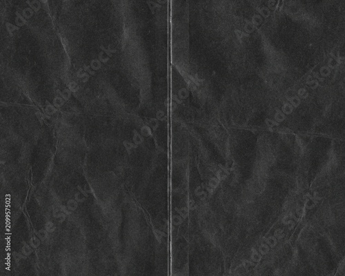Gritty folded black paper texture overlay with distressed creases, grunge analog scan surface and vintage film grain, realistic worn background for photo editing, posters and creative design