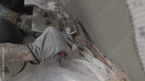 This close up video shows a construction worker hands smoothing out mortar on a metal lathe wall using multiple trowels.