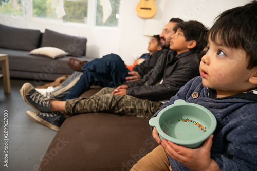 Close-up of a Hispanic toddler holding a snack bowl during family movie night.