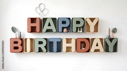 A vibrant 'Happy Birthday' message in colorful block letters on a minimalist white wall. Excellent copy space for advertising, news, and celebratory content.