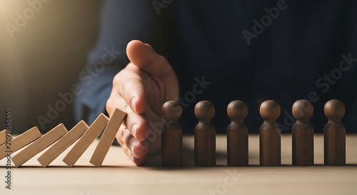 Business person stopping domino effect with wooden figures business protection