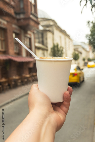 Hand holding hot Turkish salep drink on Istanbul street