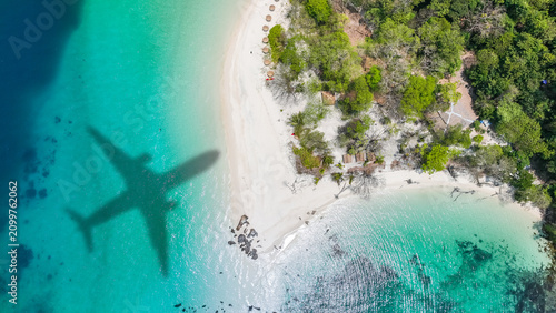 Aerial view of shadow passenger plane silhouette and sandy beach blue sea with waves at sea beach summer vacation sea travel concept	
