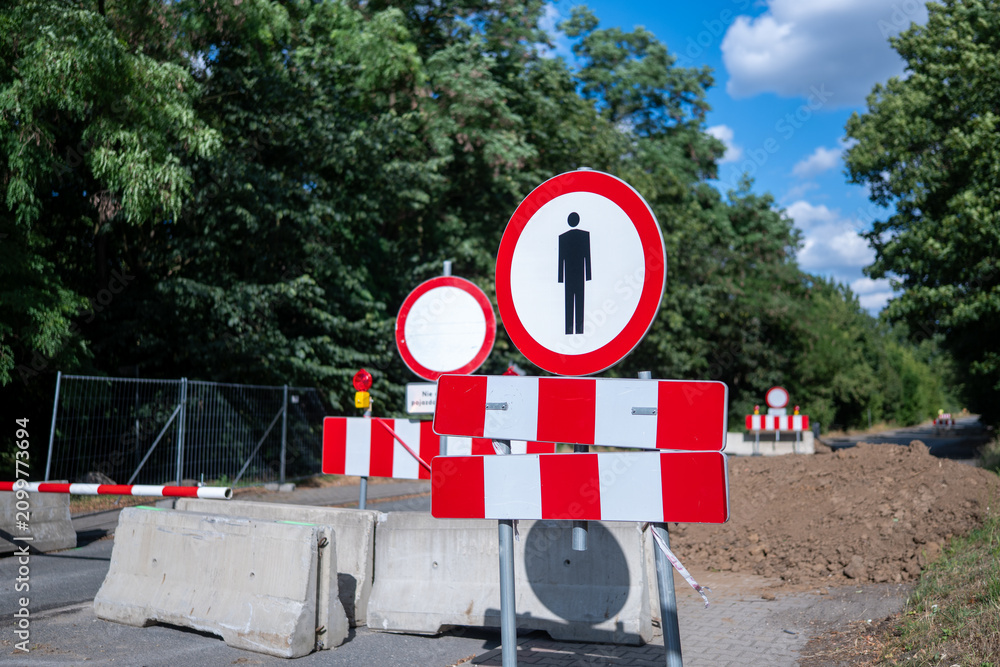 Obraz premium Znaki zakazu ruchu oraz zakazu ruchu pieszych blokujące wstęp do remontowanego odcinka drogi odgrodzone betonowymi barierkami uniemożliwiającymi przejazd w porze letniej w zachodniej Polsce