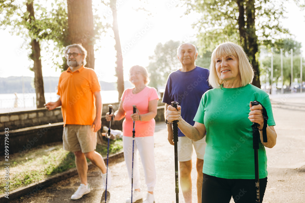 Obraz premium Seniors enjoying nordic walking outdoors for health and fitness