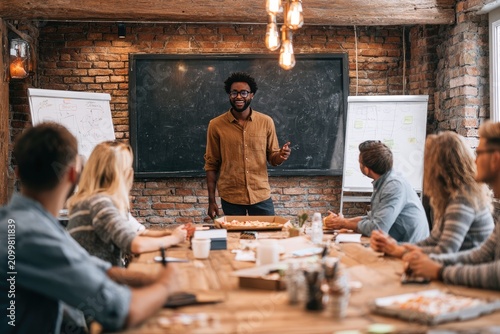 Diverse Team Brainstorms Ideas with Pizza in Rustic Boardroom