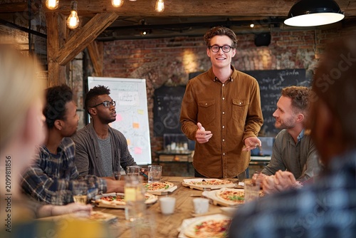 Diverse Team Brainstorms Ideas over Pizza in Rustic Boardroom