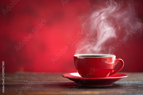 Drink mug with steam escaping from hot tea cup red in room wall red is background. Artistic photo of antique Chinese cera. Autumn tones, tea, coffee mulled wine on vintage floor.	