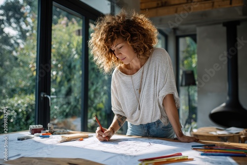 Woman Architect Drawing House Plans at Desk with Colorful Pencils