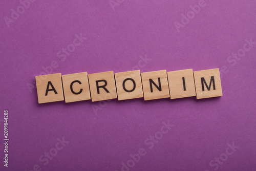 Konstfotografi Wooden letter tiles spelling acronym on a purple background, representing abbreviations, language, education, communication, writing, terminology, and learning concepts