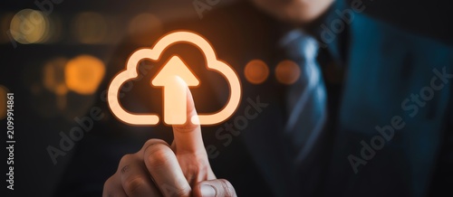 Businessman touching a glowing cloud icon with an upload arrow symbol for data storage concept
