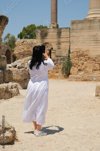 Canvastavla A woman near the great marble column of Carthage taking a photo using smartphone