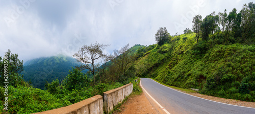 This breathtaking, wide panoramic shot captures the lush, emerald-green peaks of Charmadi Ghat in the Western Ghats of Karnataka, India.