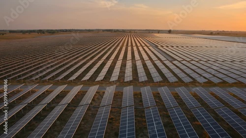Aerial view of vast solar panel farm at golden hour, renewable energy concept