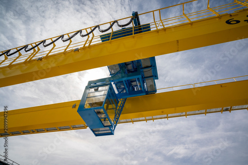 Heavy duty yellow overhead gantry crane in a logistics or construction yard.