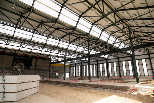 Interior of large industrial workshop under construction with steel frame and glass roof.