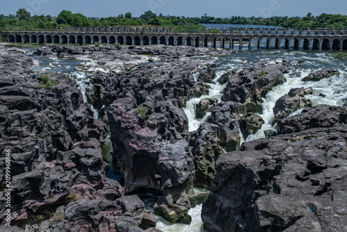 A high-angle shot of the naturally formed basalt rock potholes, locally known as Ranjan Khalge, carved over centuries by the Kukadi River in Nighoj, Ahmednagar district, Maharashtra, India.