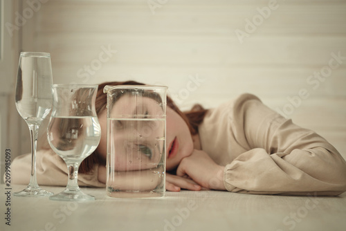 A young girl with long red hair is lying on a light wooden table