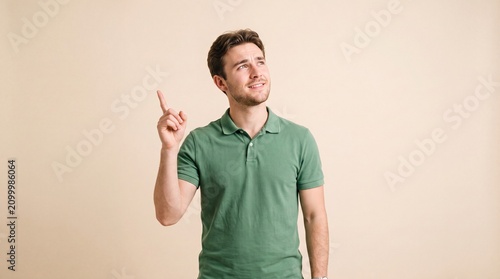 A young man with dark hair wearing a green polo shirt pointing his finger upwards while ad social media download thambnail template event festive festival 2026 2027 2028