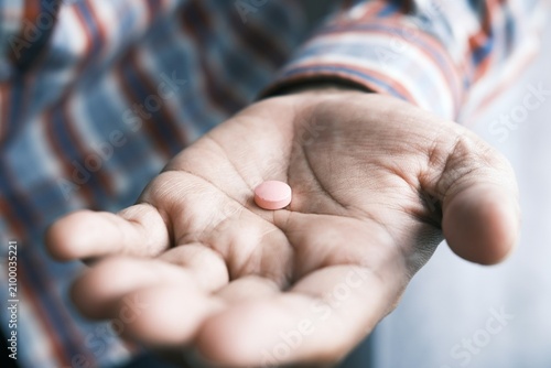 A single round medical pill lying in an open human palm close up