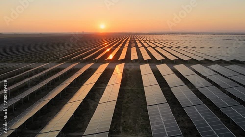 Aerial view of vast solar panel farm at golden hour, renewable energy concept