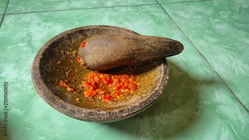 Fotografía Traditional Indonesian stone mortar and pestle with freshly ground spicy chili sambal