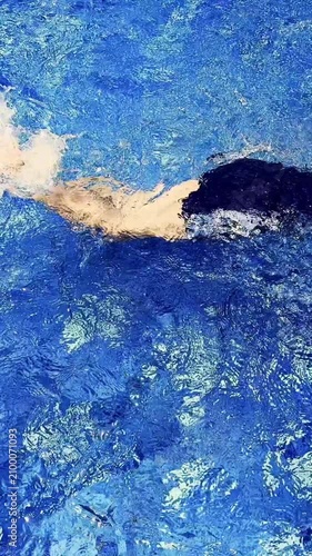 Vertical view of vivid blue pool water forming sparkling ripples and flowing abstract patterns.