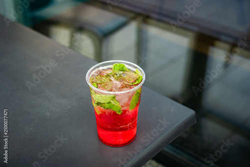 Strawberry lemonade in a takeaway cup. Bright red strawberry lemonade with mint and ice. Refreshing non-alcoholic summer beverage for hot weather.