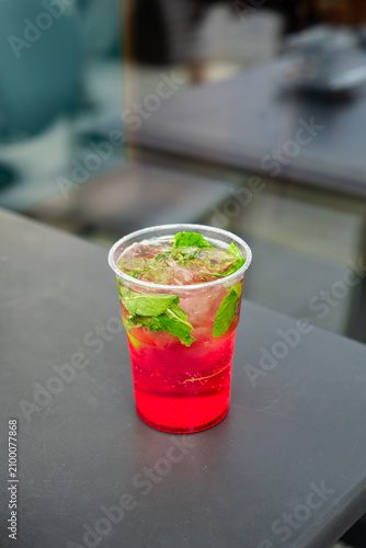 Refreshing fruit lemonade in a plastic cup. Homemade strawberry lemonade with fresh fruit, mint and ice. Cold refreshing drink for warm summer days.