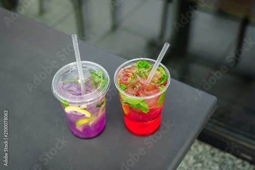 Fresh fruit lemonades with ice and mint. Bright homemade fruit lemonades with citrus slices, mint and ice served in takeaway cups. Refreshing summer drinks.