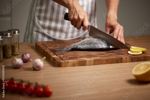 Fotografía Chef slicing fresh sea bream fish on cutting board