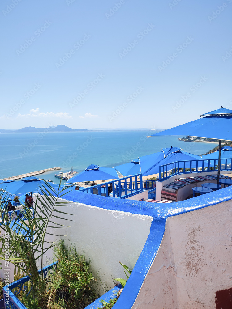 Obraz premium Blue beach umbrellas overlooking terraces and sea in sidi bou said town