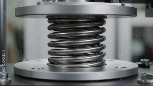 Close-Up View of a Metallic Compression Spring Mounted on a Testing Device Illustrating Mechanical Engineering and Material Testing Processes