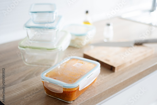Glass meal prep containers with prepared food on kitchen table