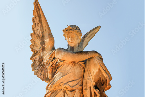 Stone angel statue embracing a memorial urn in a historic cemetery.