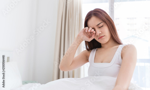 Portrait of beauty asian sexy woman rubbing eye after waking up, awaking on the bed (sleep). Young asian girl morning tiredness, fatigue, or lack of sleep relax peaceful morning routine yawn