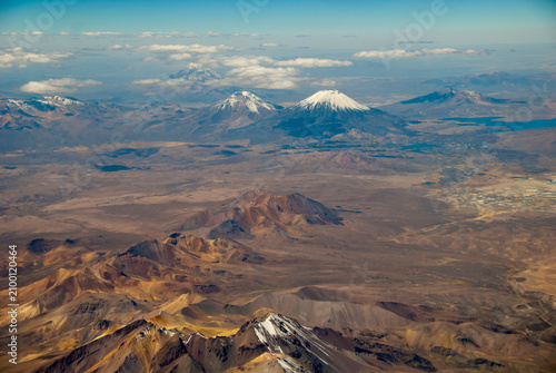 Bolivia, Chile, Inland, the Western Range or Cordillera Occidental, at the border between Bolivia and Chile, with volcanoes and high peaks with perennial snows against cloudy sky