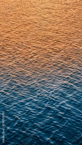 A water surface with a single floating leaf drifting across ripples, vertical 9:16 top-down view.