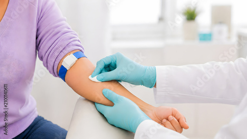 Doctor Pressing Cotton Pad On Arm After Blood Draw