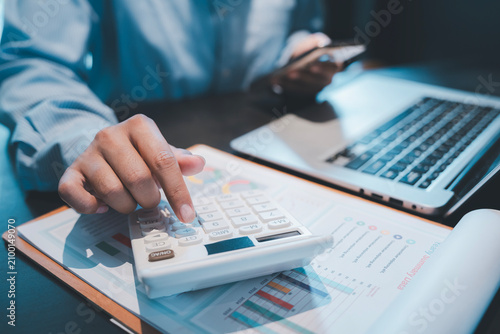Financial auditing and business accounting concept accountant hands using white calculator over data chart documents near laptop for analyzing corporate budget expense and estimating investment profit