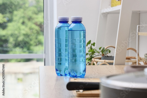 Fotografie Two blue plastic water bottles filled with clear liquid on a wooden table indoor