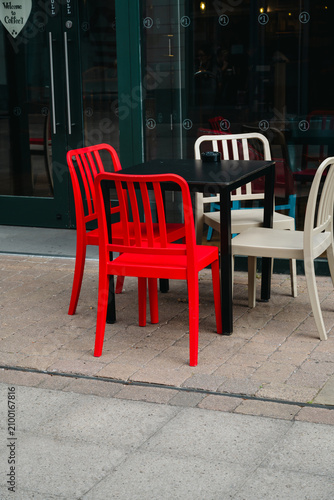Corby, Northamptonshire, United Kingdom - July 15, 2026: Empty outdoor cafe tables and red chairs in modern shopping center