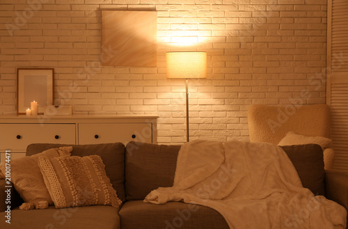 Cozy sofa and glowing lamp ...