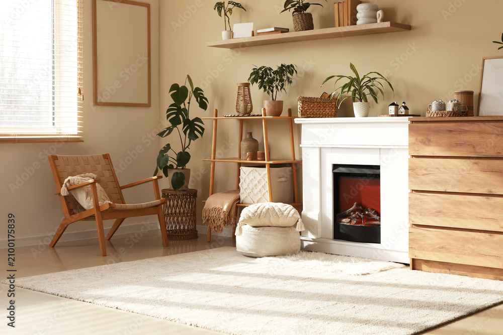 Obraz premium Interior of living room with fireplace, shelving unit and wicker chair near beige wall