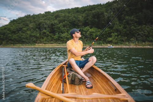 Man fishing from wooden canoe